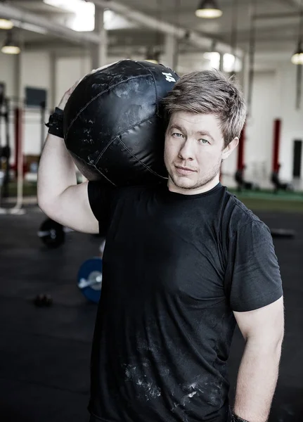Мужчина, несущий медицинский мяч на плече в спортзале Лицензионные Стоковые Изображения