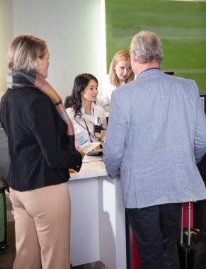 Üst düzey yolcular Check-in Havaalanı masasında yardımcı personel