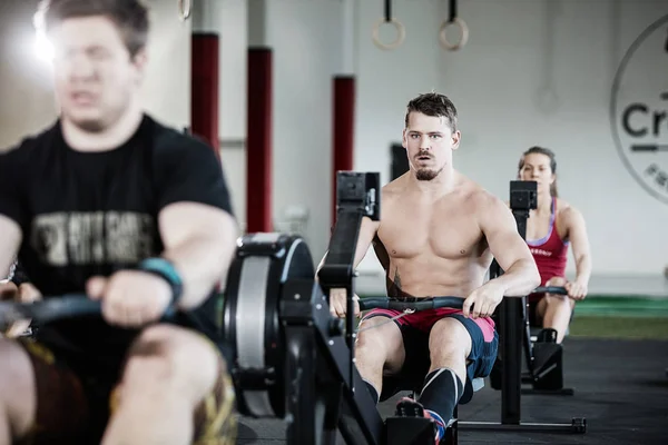 Homem muscular exercitando na máquina de remo no ginásio — Fotografia de Stock