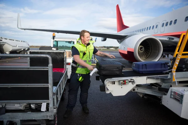 Trabajador Arreglando el equipaje en el remolque conectado al avión — Foto de Stock