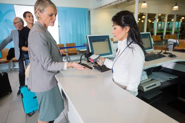 Recepcionista del aeropuerto escaneando código de barras en un teléfono inteligente en autobús — Foto de Stock