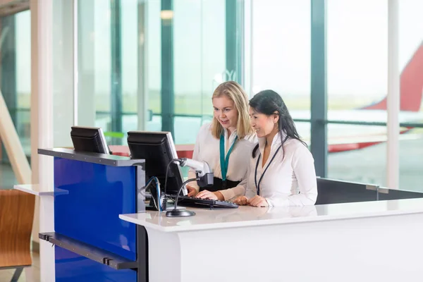 Rezeptionisten benutzen Computer am Schalter im Flughafen — Stockfoto