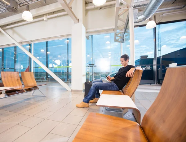 Man met mobiele telefoon tijdens het wachten voor zijn vlucht — Stockfoto