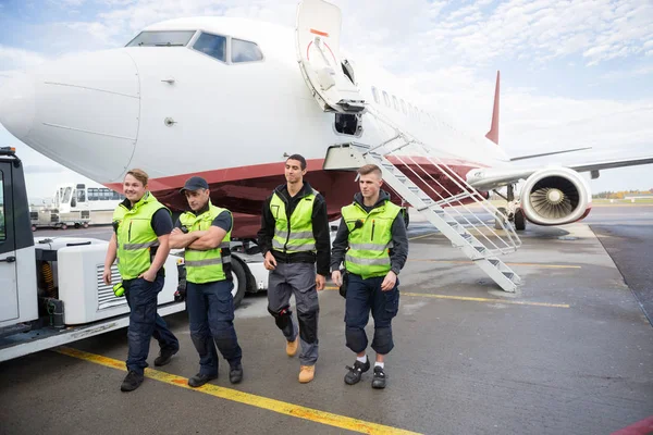 Tripulação de terra confiante andando contra avião — Fotografia de Stock