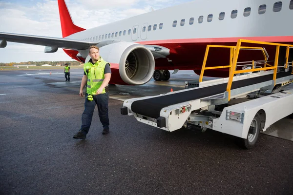 Lavoratore che cammina dal camion del trasportatore con l'aeroplano sulla pista Foto Stock