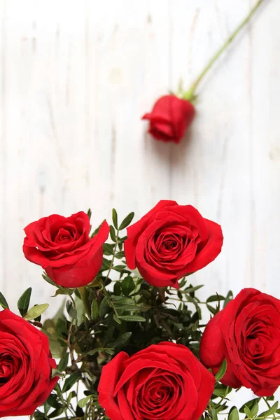 Ramo de rosas rojas en una mesa de madera — Foto de Stock