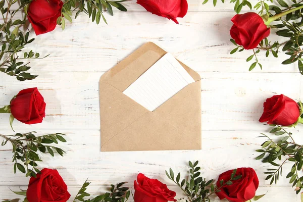 Envelope com papel em uma moldura quadrada de rosas vermelhas — Fotografia de Stock