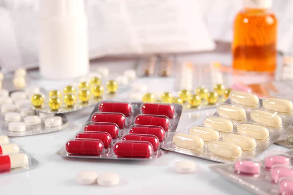 Muitas pílulas diferentes em uma mesa branca — Fotografia de Stock