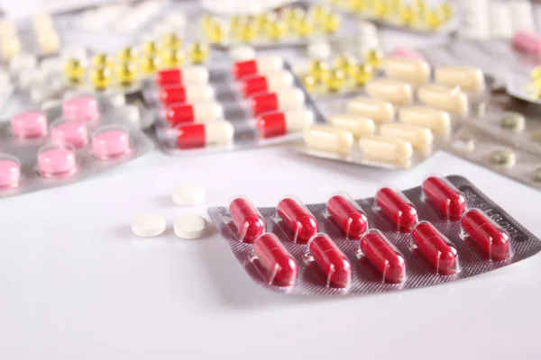 Много разных таблеток на белом столе — стоковое фото