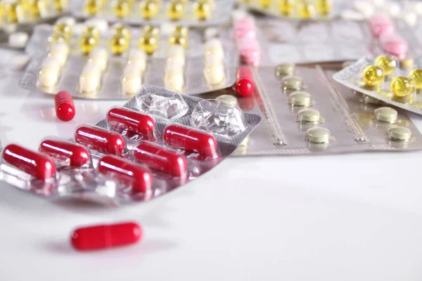 Muchas píldoras diferentes en una mesa blanca — Foto de Stock