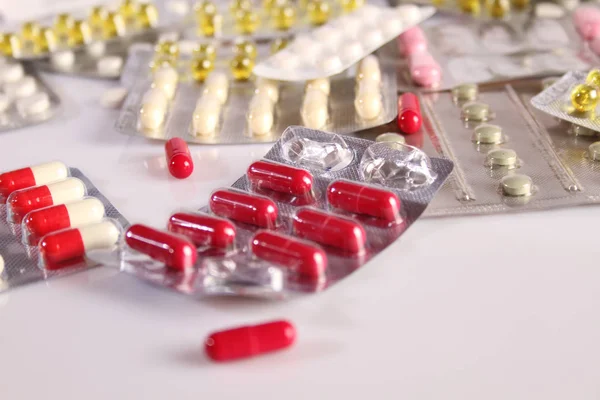 Muitas pílulas diferentes em uma mesa branca — Fotografia de Stock
