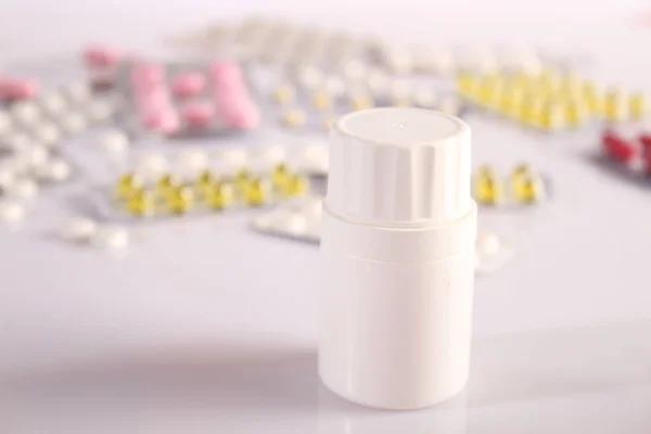 Frasco com comprimidos e um monte de comprimidos nas proximidades — Fotografia de Stock