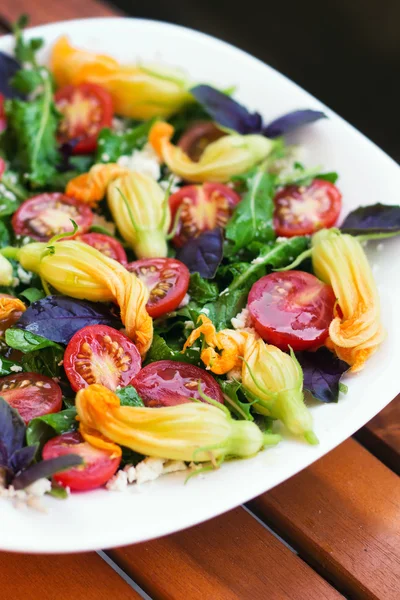Seasonal salad with arugula, cherry tomatoes, basil and zucchini flowers — Stock Photo, Image