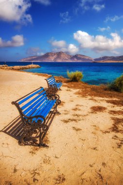Benches overlooking a beach on Pano Koufonisi island, Greece clipart