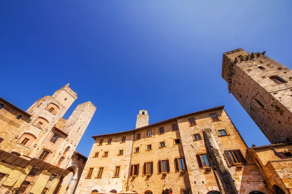 En vidvinkel skott av den medeltida arkitekturen i den Piazza della Cisterna torget San Gimignano, Italien — Stockfoto