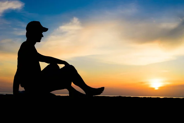 Silhouette of a man sitting near the ocean — Stock Photo, Image