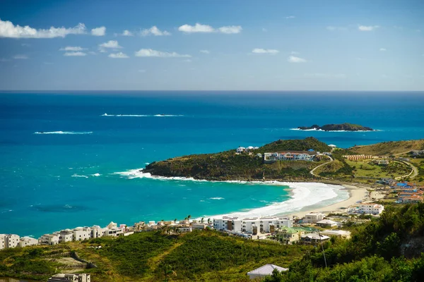 Pequeñas islas pedregosas en el mar azul con playa y casas en primer plano — Foto de Stock