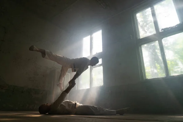 男性二人制作杂技技巧穿着疯狂的人服装在废弃的房间与阳光从窗口 — 图库照片