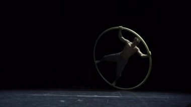 Cyr Wheel 'deki kaslı sirk sanatçısı ağır çekimde zor numaralar yapıyor. Konsantrasyon ve denge kavramı