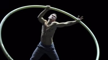 Cyr Wheel 'deki kaslı sirk sanatçısı ağır çekimde zor numaralar yapıyor. Konsantrasyon ve denge kavramı