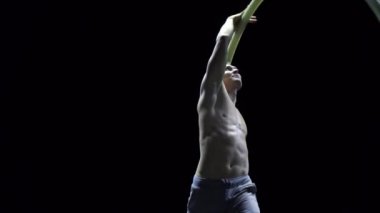 Cyr Wheel 'deki kaslı sirk sanatçısı ağır çekimde zor numaralar yapıyor. Konsantrasyon ve denge kavramı