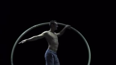 Cyr Wheel 'deki kaslı sirk sanatçısı ağır çekimde zor numaralar yapıyor. Konsantrasyon ve denge kavramı