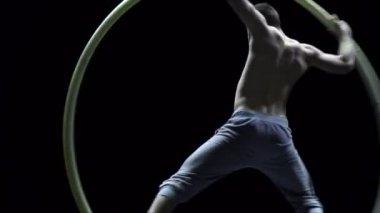 Cyr Wheel 'deki kaslı sirk sanatçısı ağır çekimde zor numaralar yapıyor. Konsantrasyon ve denge kavramı