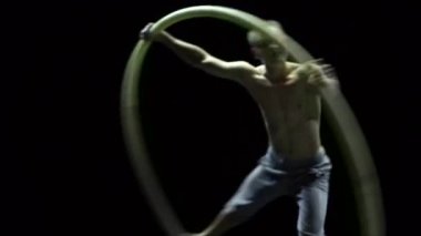 Cyr Wheel 'deki kaslı sirk sanatçısı ağır çekimde zor numaralar yapıyor. Konsantrasyon ve denge kavramı