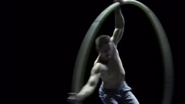 Muskuløs sirkusartist i bilhjulet som gjør vanskelige triks, sakte film. Konsentrasjons- og balansebegrep – stockvideo