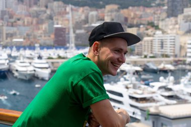 Genç yakışıklı adam arka planda bulanık yelkenli ve gemilerile gemide gülümseyen. Monte Carlo, Monako