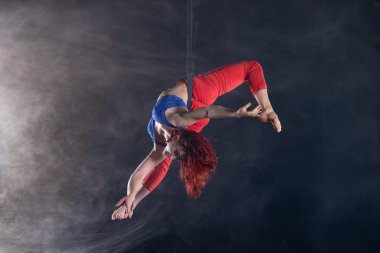 Siyah arka plan üzerinde hava kayışları üzerinde redhead ile Kadın atletik, seksi ve esnek hava sirk sanatçısı