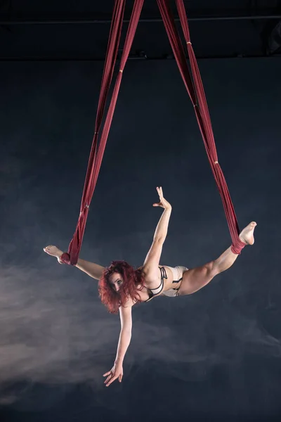 Weibliche athletische, sexy und flexible Zirkusartistin mit Rotschopf, der auf der Seide in der Luft tanzt — Stockfoto