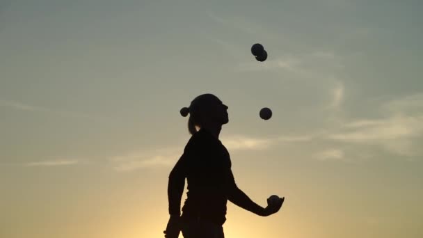 Zirkusartistin jongliert mit Bällen bei buntem Sonnenuntergang — Stockvideo