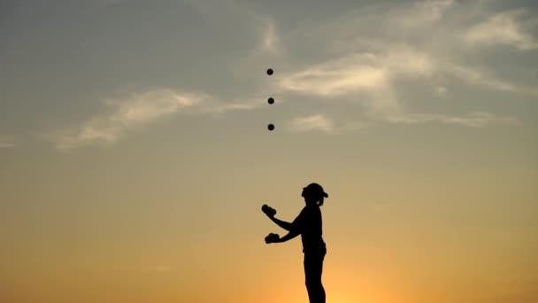 Artista de circo malabarismo com bolas no pôr do sol colorido — Vídeo de Stock