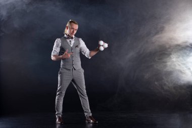 Hokkabaz beyaz topları olan bir işadamı gibi takım elbise giyiyor. Başarı ve yönetim kavramı