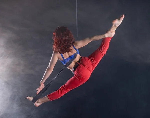 Mujer atlética, sexy y flexible artista de circo aéreo con pelirroja en correas aéreas sobre fondo negro —  Fotos de Stock