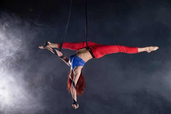 Weibliche athletische, sexy und flexible Zirkusartistin mit Rotschopf auf Antennenriemen auf schwarzem Hintergrund — Stockfoto