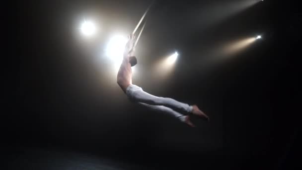 Masculino muscular circo artista no aéreo tiras fazendo forte truques no ar no preto fundo — Vídeo de Stock