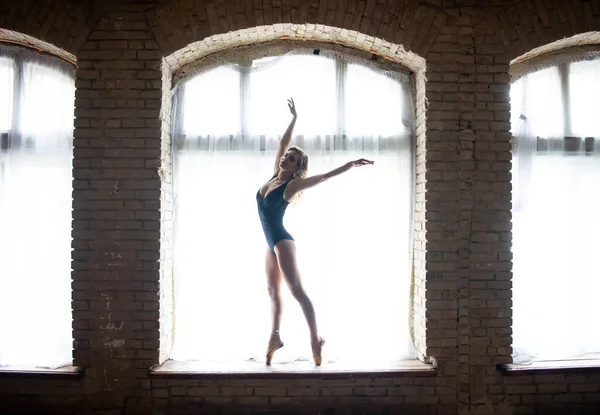 Silueta unei tinere balerine în formă bună care stă pe fereastra imensă. Conceptul de stil de viață sănătos — Fotografie, imagine de stoc