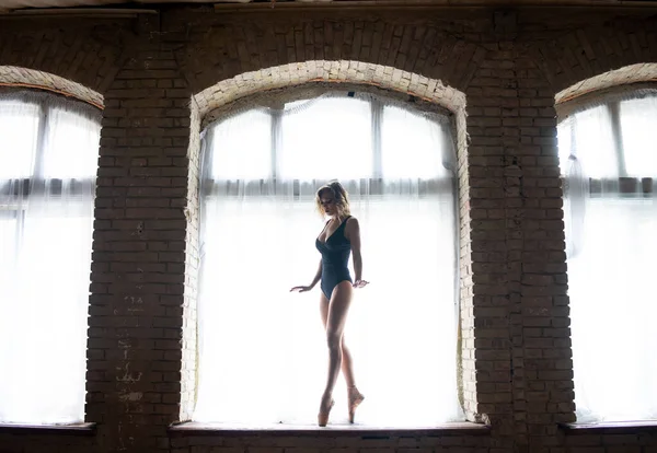Silhueta de uma bailarina jovem de boa forma em pé na enorme janela. Conceito de saudável e beleza — Fotografia de Stock