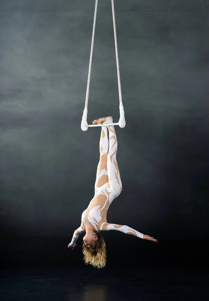 Una giovane ragazza esegue gli elementi acrobatici nel trapezio dell'aria. Studio prestazioni di ripresa su uno sfondo nero — Foto Stock