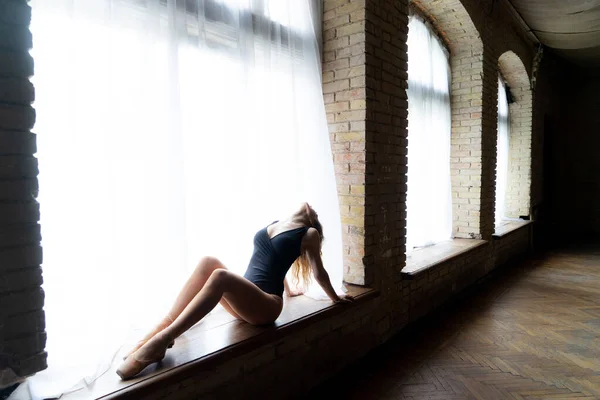 Bela bailarina no fato de banho preto posando na grande janela no salão de luz. Conceito de estilo de vida saudável — Fotografia de Stock