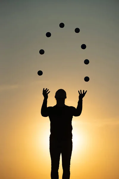 Silhueta de malabarista com bolas no pôr do sol colorido — Fotografia de Stock