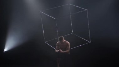 Sirk erkek kaslı sanatçısı siyah arka planda küp aksesuarlarıyla hokkabazlık yapıyor. Konsantrasyon, kontrol, güç ve güç kavramı