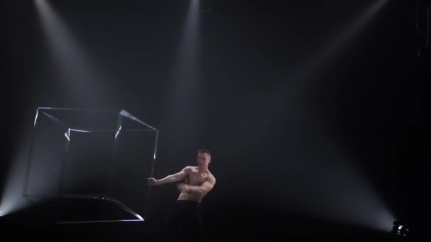 サーカスの男性筋肉のパフォーマーは黒の背景でキューブの小道具をジャグリングしてトリックを作っています濃度、制御、力、力の概念 — ストック動画