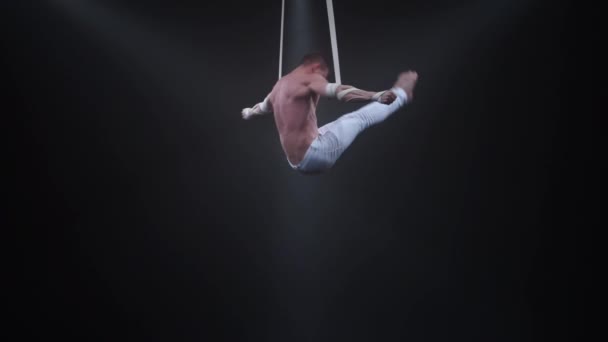 Muscular circus aerialist on the aerial straps in black studio — Stock Video