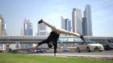 Akrobat bir elinde bulanık Dubai şehir manzarası ile dengesini koruyor. Modern ve sağlıklı yaşam tarzı kavramı.