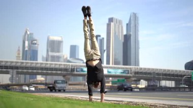 Akrobat bir elinde bulanık Dubai şehir manzarası ile dengesini koruyor. Modern ve sağlıklı yaşam tarzı kavramı.