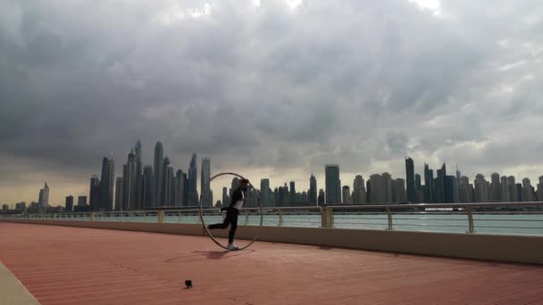 Cyr Wheel artist wearing black and white smart clothes with cityscape background of Dubai during sunset — Stock Video