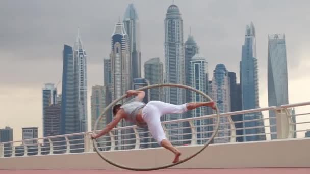 Artista Cyr Wheel com fundo cityscape de Dubai durante o pôr do sol — Vídeo de Stock